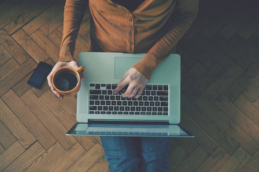 Person using a laptop while drinking a coffee