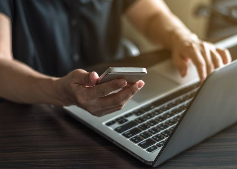 A person using their phone to log in with 2FA on a laptop