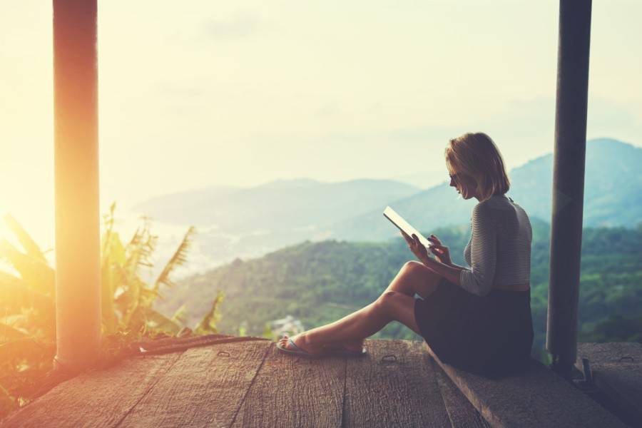 A person using a tablet overlooking a rainforest