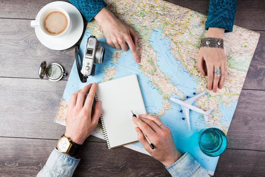 A pair of hands pointing to a map and writing notes.